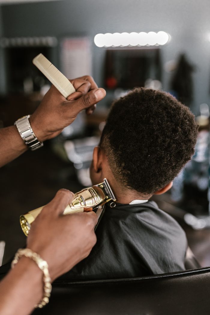 A barber skillfully trims a client's hair in a stylish, contemporary barber shop.